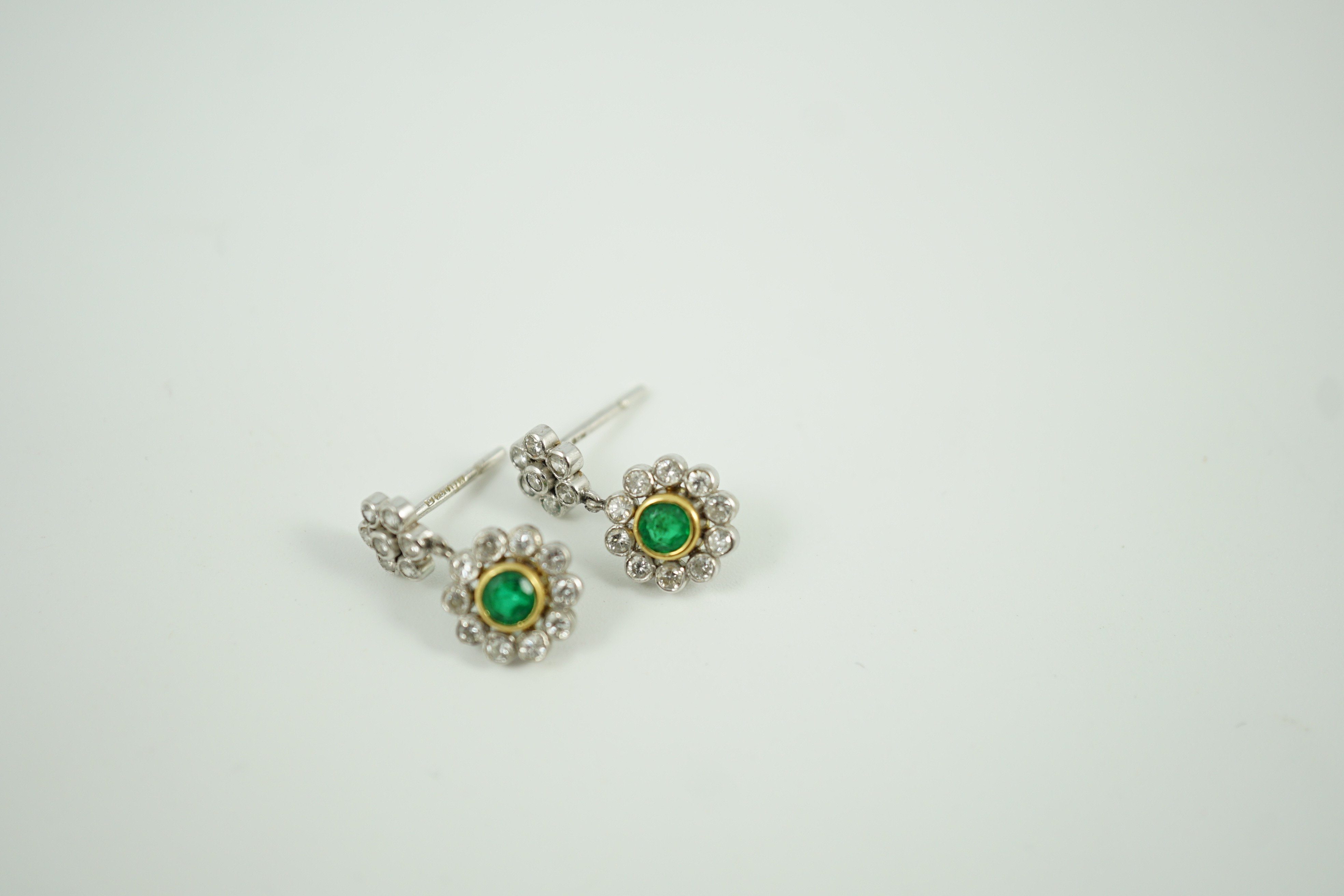 A modern pair of 18ct white gold, emerald and diamond cluster set drop earrings, 16mm, gross weight 3 grams.
